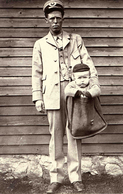 Postal worker carrying child in a mailbag